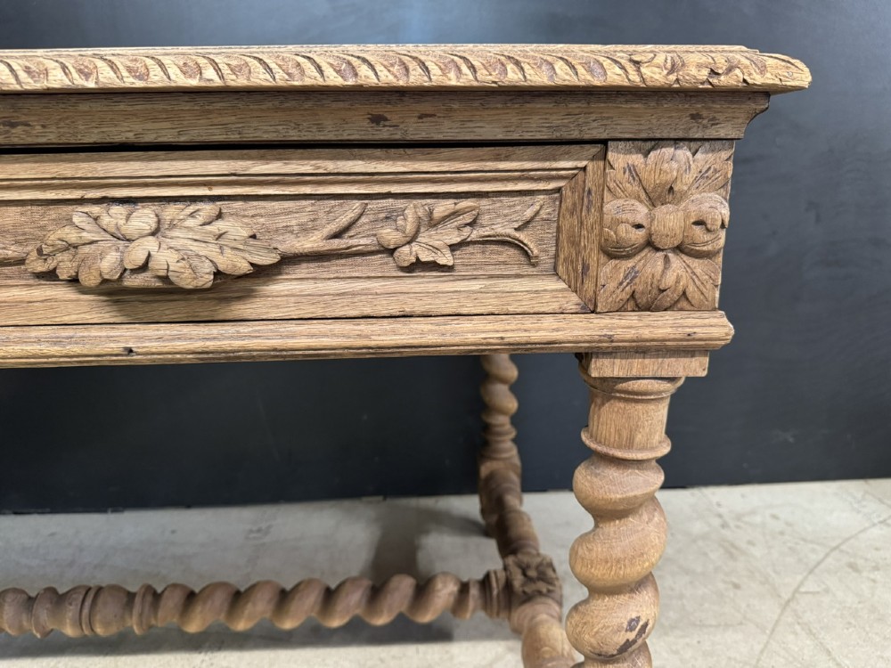 A French bleached oak writing desk featuring hand-carved floral drawer fronts, egg-and-dart moulding, turned barley twist legs, and an H-stretcher base. View VII