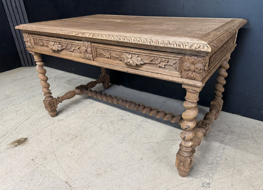 A French bleached oak writing desk featuring hand-carved floral drawer fronts, egg-and-dart moulding, turned barley twist legs, and an H-stretcher base. View VIII