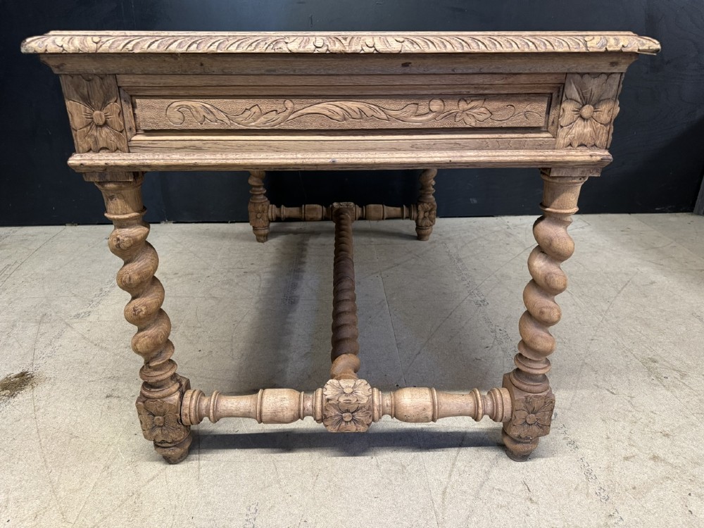 A French bleached oak writing desk featuring hand-carved floral drawer fronts, egg-and-dart moulding, turned barley twist legs, and an H-stretcher base. View X