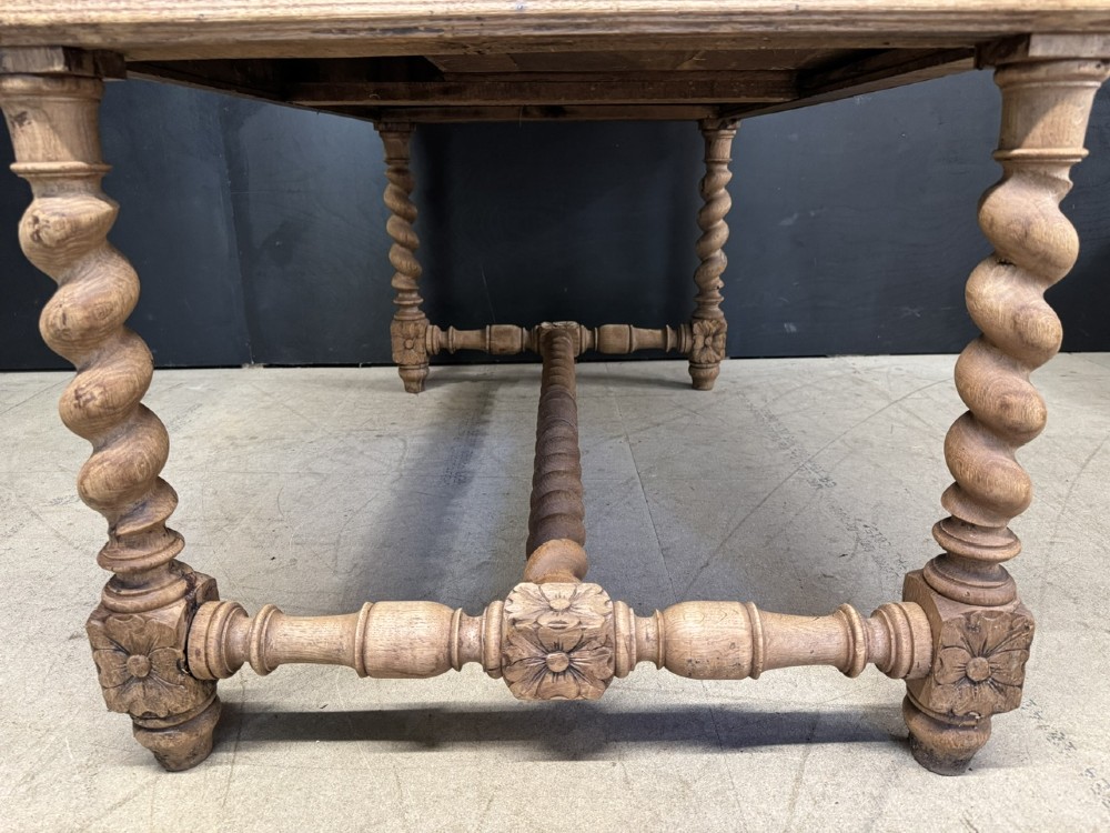 A French bleached oak writing desk featuring hand-carved floral drawer fronts, egg-and-dart moulding, turned barley twist legs, and an H-stretcher base. View XI