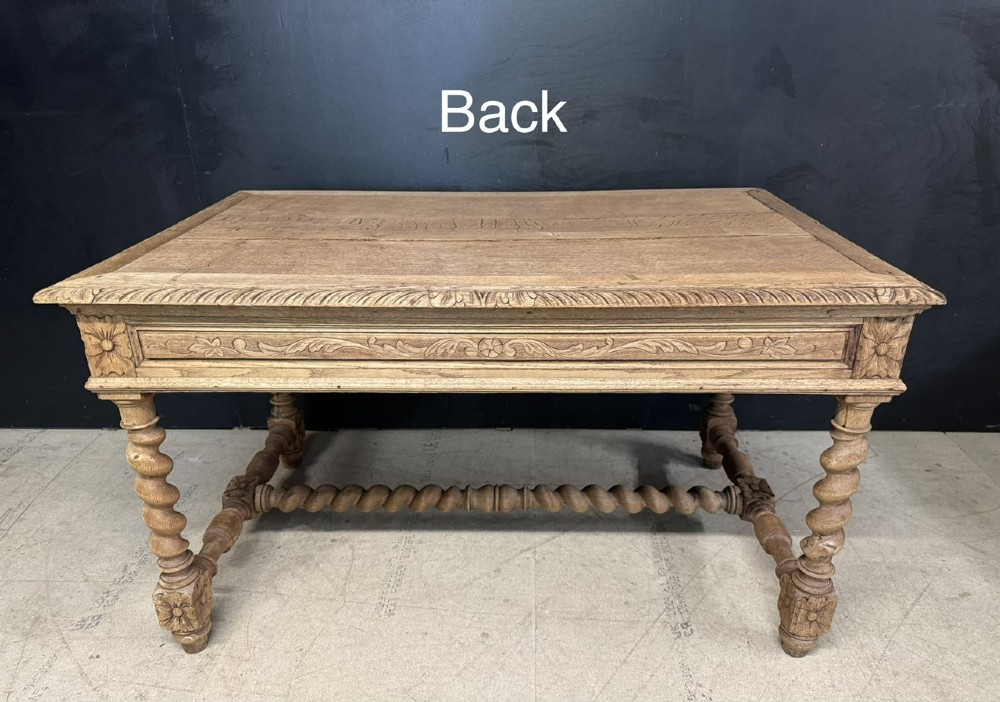 A French bleached oak writing desk featuring hand-carved floral drawer fronts, egg-and-dart moulding, turned barley twist legs, and an H-stretcher base. View XII