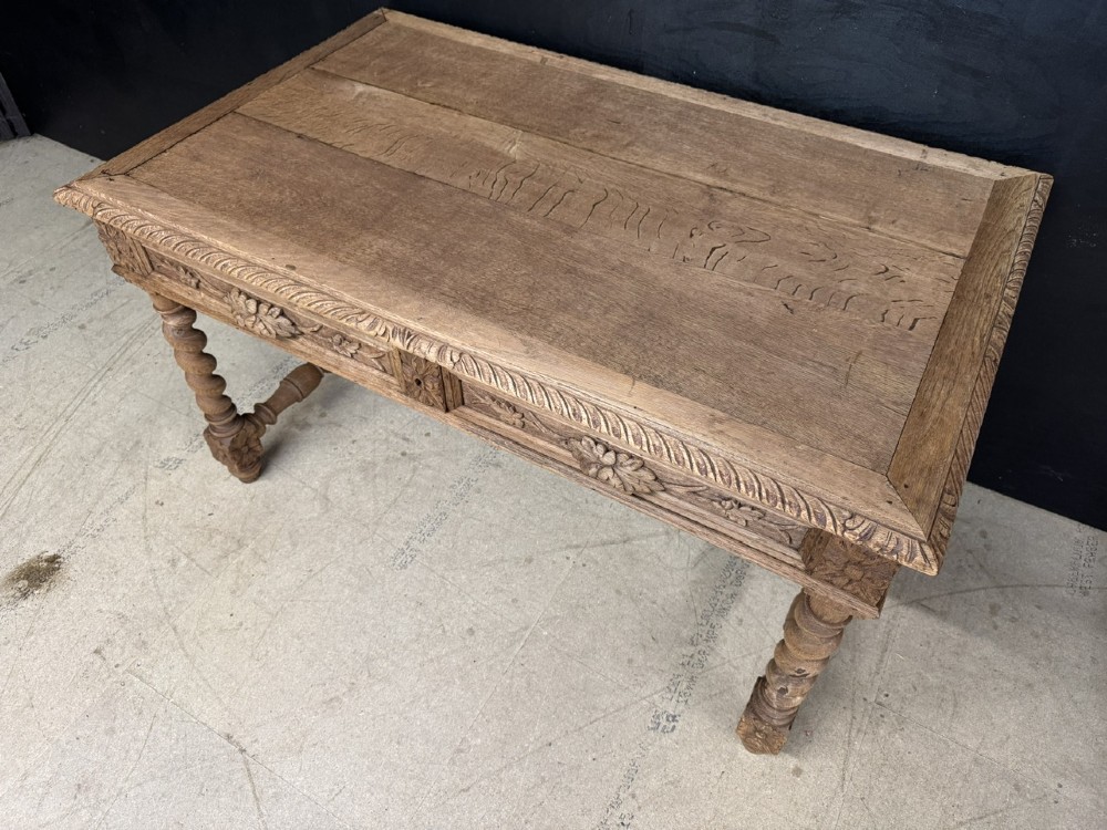 A French bleached oak writing desk featuring hand-carved floral drawer fronts, egg-and-dart moulding, turned barley twist legs, and an H-stretcher base. View XV