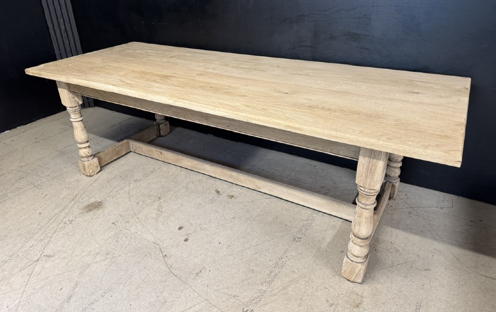 A large light oak farmhouse dining table featuring a solid plank top, turned legs, and an H-shaped stretcher base. View II