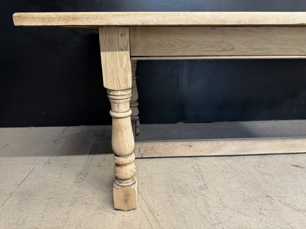 A large light oak farmhouse dining table featuring a solid plank top, turned legs, and an H-shaped stretcher base. View IX