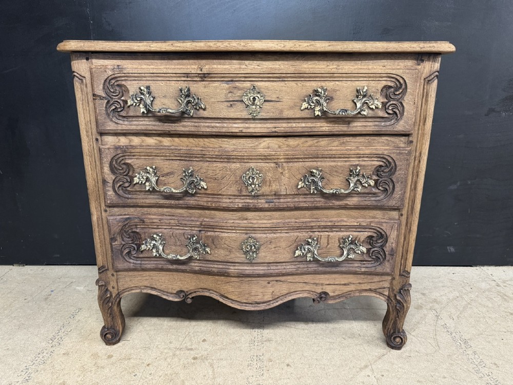 A French provincial bleached oak commode featuring three drawers with carved decorative mouldings and cast metal handles. View II