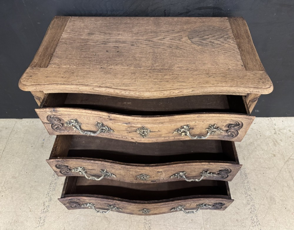 A French provincial bleached oak commode featuring three drawers with carved decorative mouldings and cast metal handles. View III