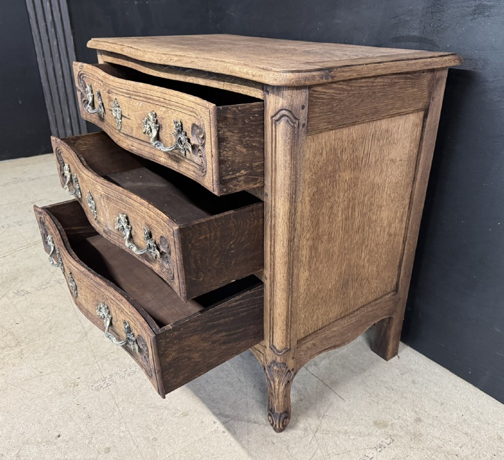 A French provincial bleached oak commode featuring three drawers with carved decorative mouldings and cast metal handles. View IV