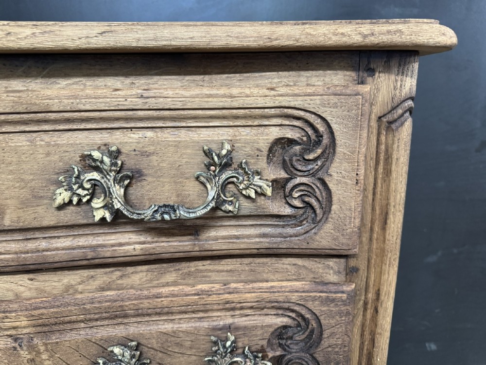 A French provincial bleached oak commode featuring three drawers with carved decorative mouldings and cast metal handles. View V