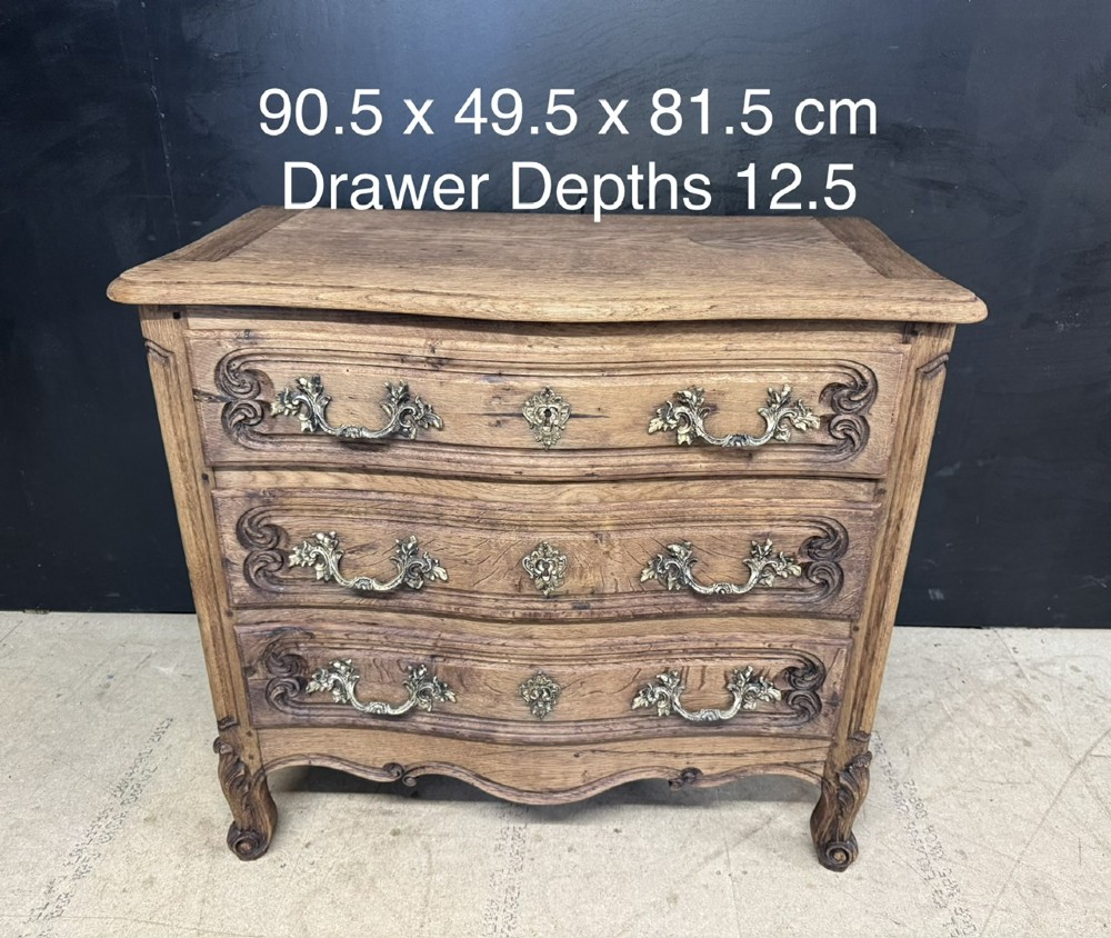 A French provincial bleached oak commode featuring three drawers with carved decorative mouldings and cast metal handles. View XII