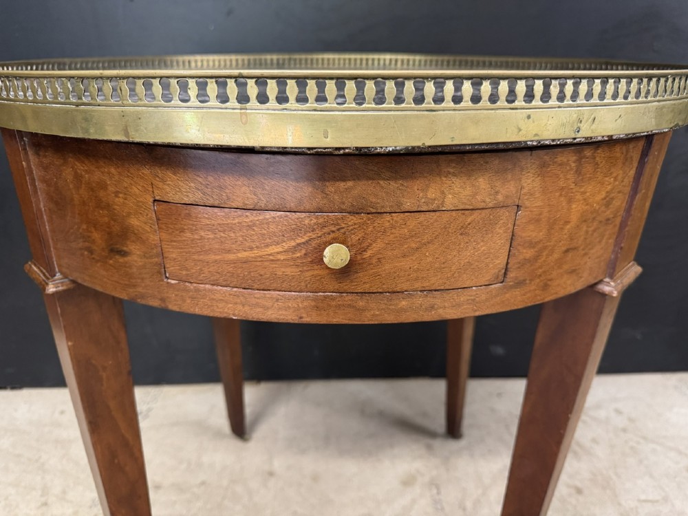 A circular French Louis XVI style lamp table featuring a dark veined marble top, a pierced brass gallery rim, a single drawer, and four square tapered legs. View IV