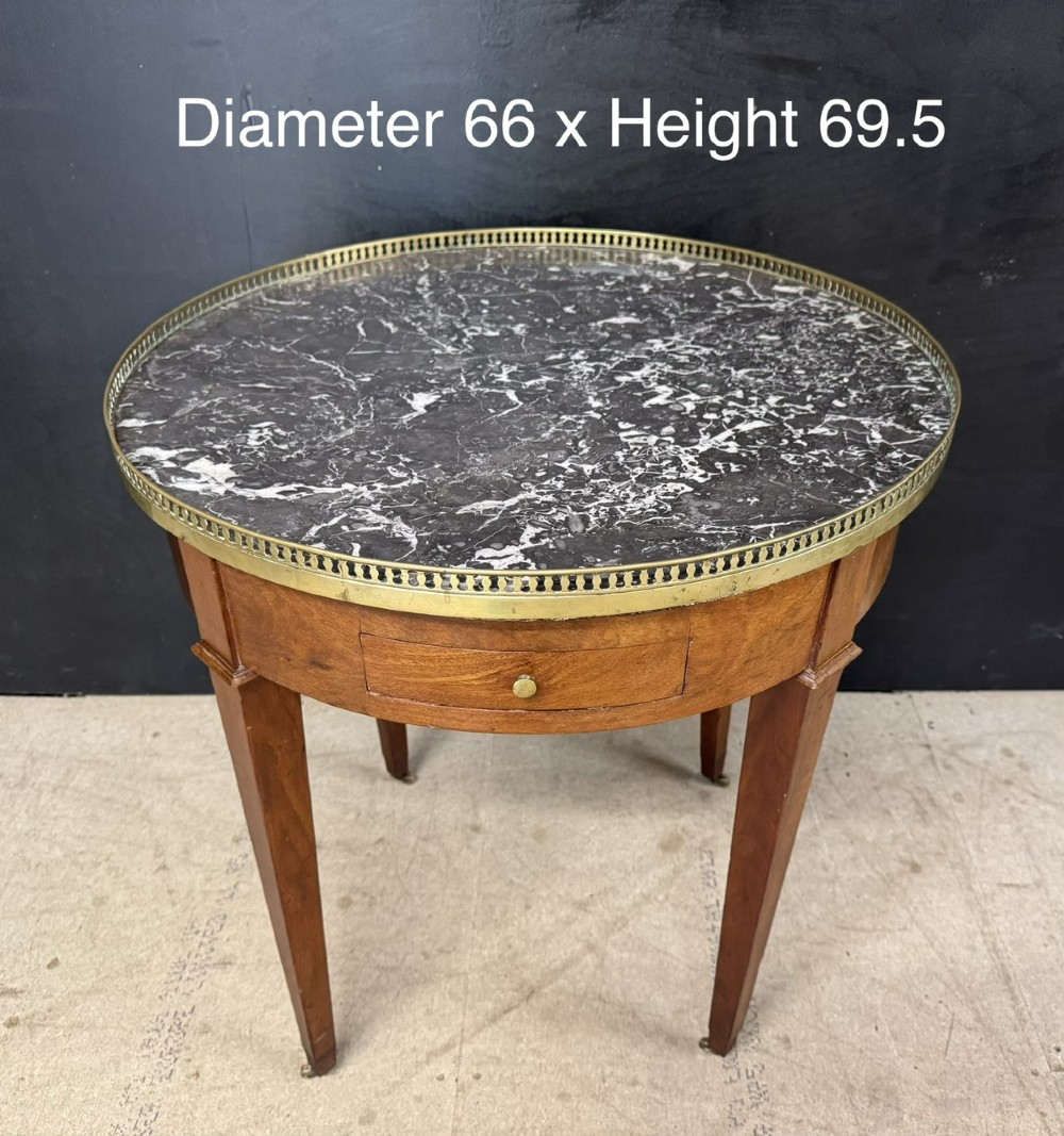 A circular French Louis XVI style lamp table featuring a dark veined marble top, a pierced brass gallery rim, a single drawer, and four square tapered legs. View IX