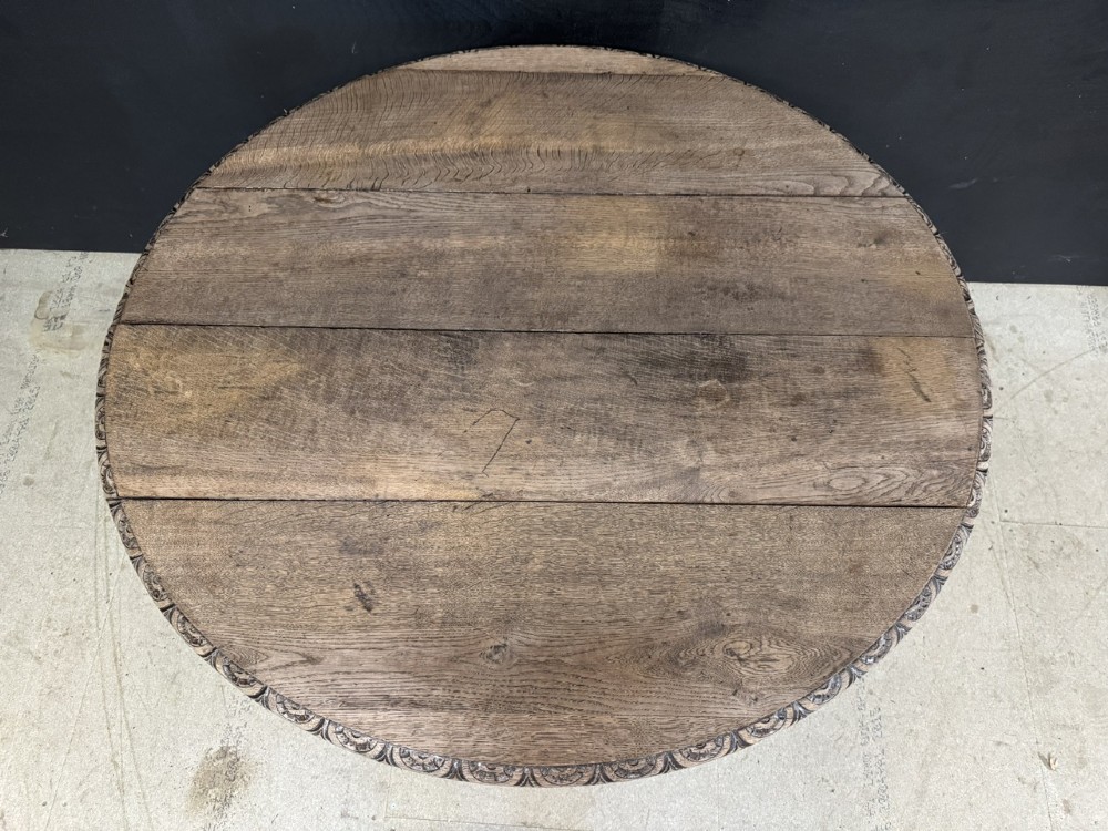 A circular French carved oak hunting table featuring an intricately carved rim and a central pedestal supported by carved lion head feet. View III