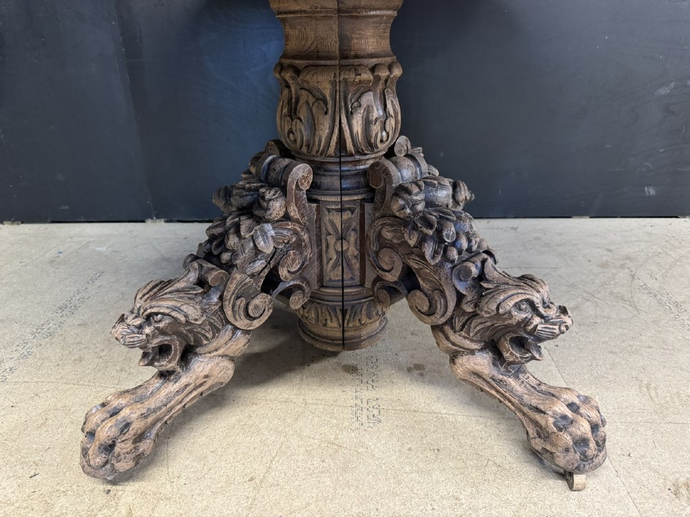 A circular French carved oak hunting table featuring an intricately carved rim and a central pedestal supported by carved lion head feet. View IV