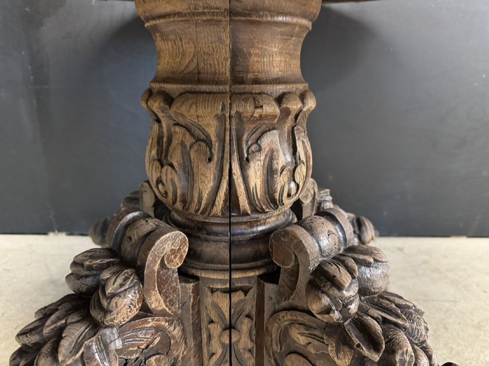 A circular French carved oak hunting table featuring an intricately carved rim and a central pedestal supported by carved lion head feet. View VII