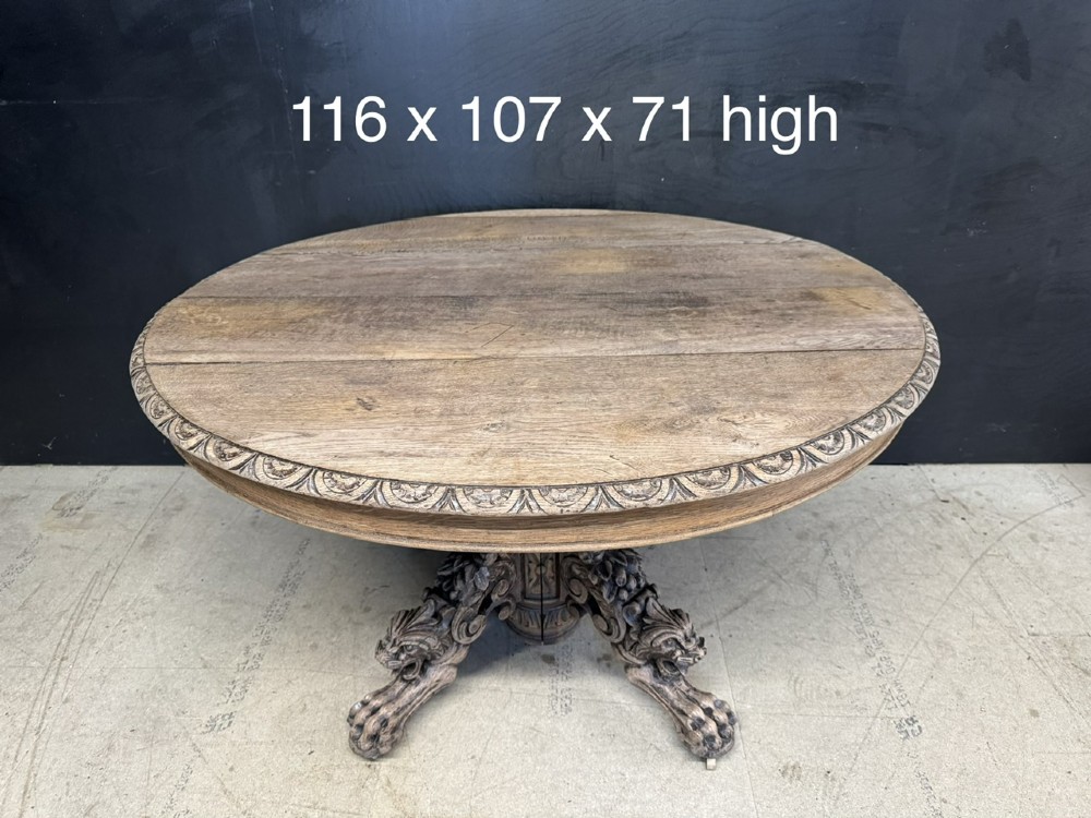 A circular French carved oak hunting table featuring an intricately carved rim and a central pedestal supported by carved lion head feet. View XI