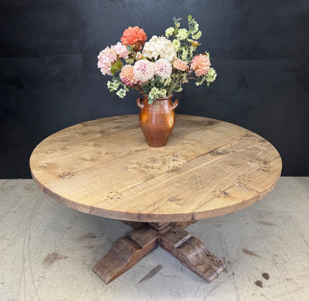 A large round oak dining table featuring a planked top and a substantial wooden cross-pedestal base. View II