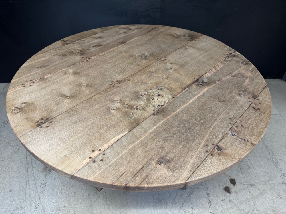 A large round oak dining table featuring a planked top and a substantial wooden cross-pedestal base. View VI