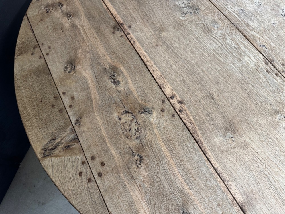 A large round oak dining table featuring a planked top and a substantial wooden cross-pedestal base. View VIII