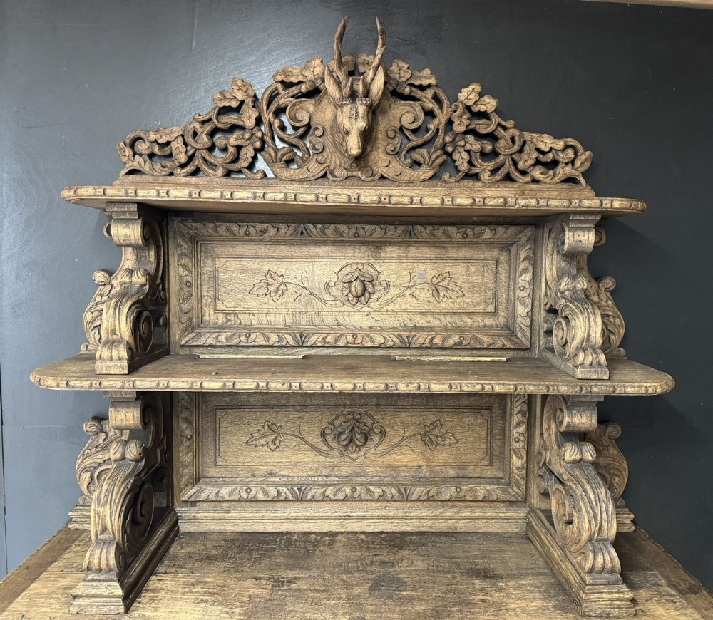 A dark oak French hunting sideboard featuring a carved stag head top pediment, open middle shelves, and lower cabinet doors decorated with carved game birds. View III