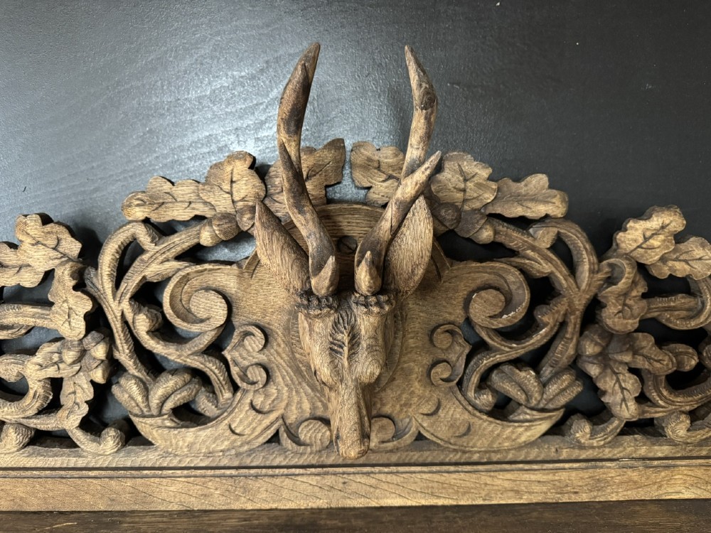 A dark oak French hunting sideboard featuring a carved stag head top pediment, open middle shelves, and lower cabinet doors decorated with carved game birds. View IV