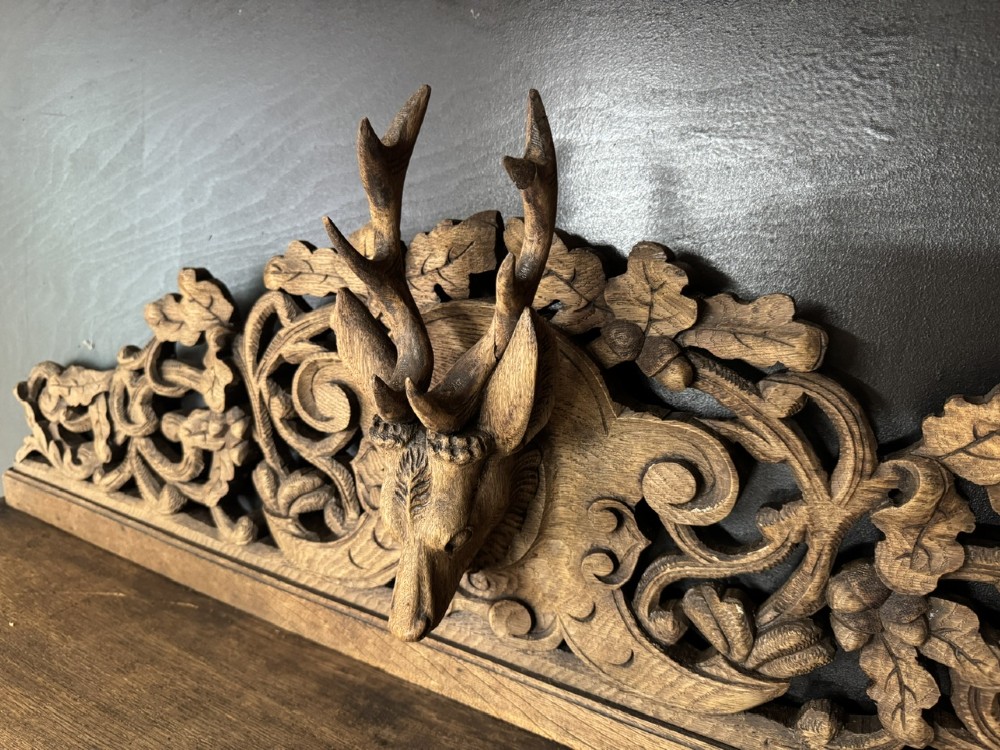 A dark oak French hunting sideboard featuring a carved stag head top pediment, open middle shelves, and lower cabinet doors decorated with carved game birds. View V