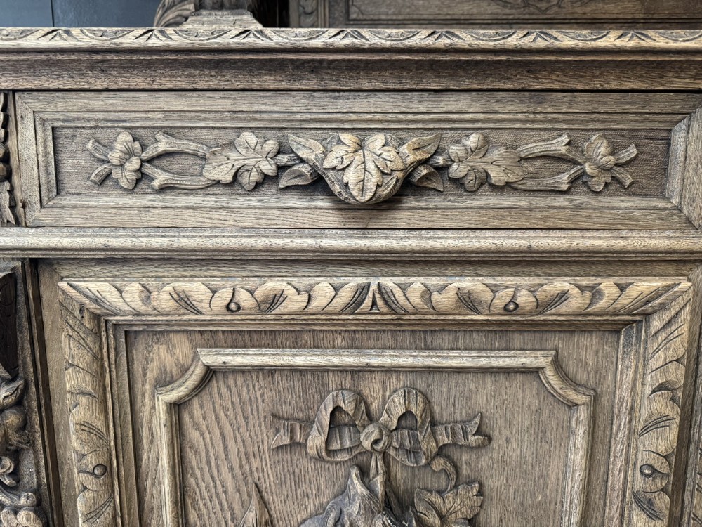 A dark oak French hunting sideboard featuring a carved stag head top pediment, open middle shelves, and lower cabinet doors decorated with carved game birds. View IX
