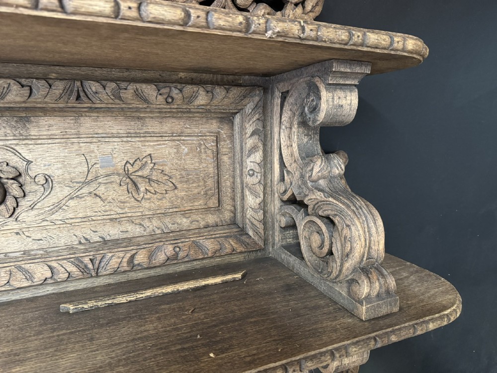 A dark oak French hunting sideboard featuring a carved stag head top pediment, open middle shelves, and lower cabinet doors decorated with carved game birds. View X