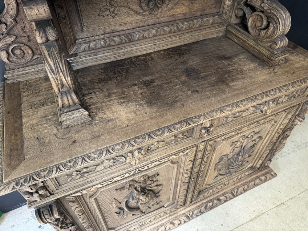 A dark oak French hunting sideboard featuring a carved stag head top pediment, open middle shelves, and lower cabinet doors decorated with carved game birds. View XI