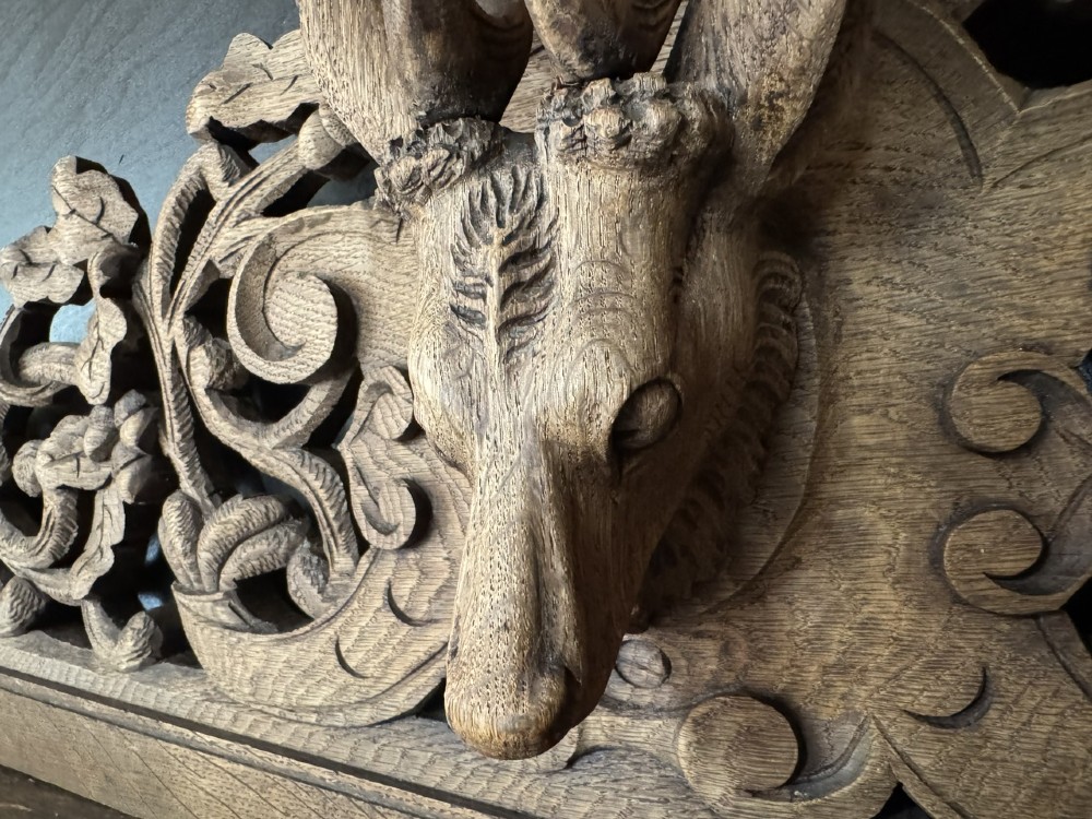 A dark oak French hunting sideboard featuring a carved stag head top pediment, open middle shelves, and lower cabinet doors decorated with carved game birds. View XIII