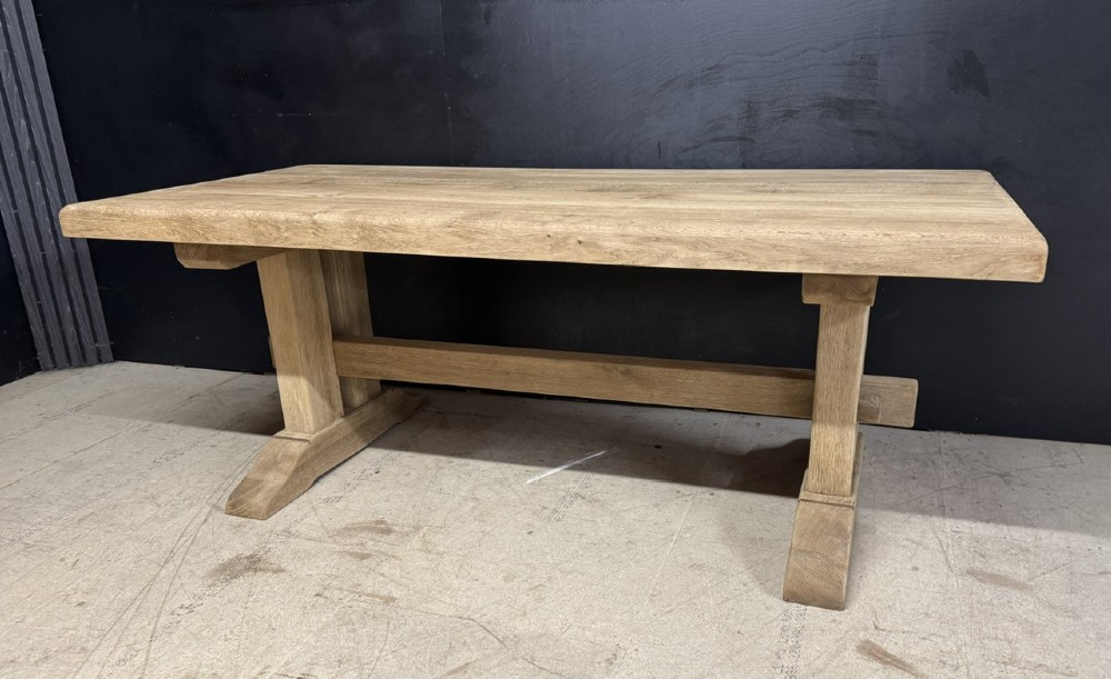 A solid bleached oak dining table featuring a thick rectangular top supported by a sturdy trestle base and central stretcher rail. View V