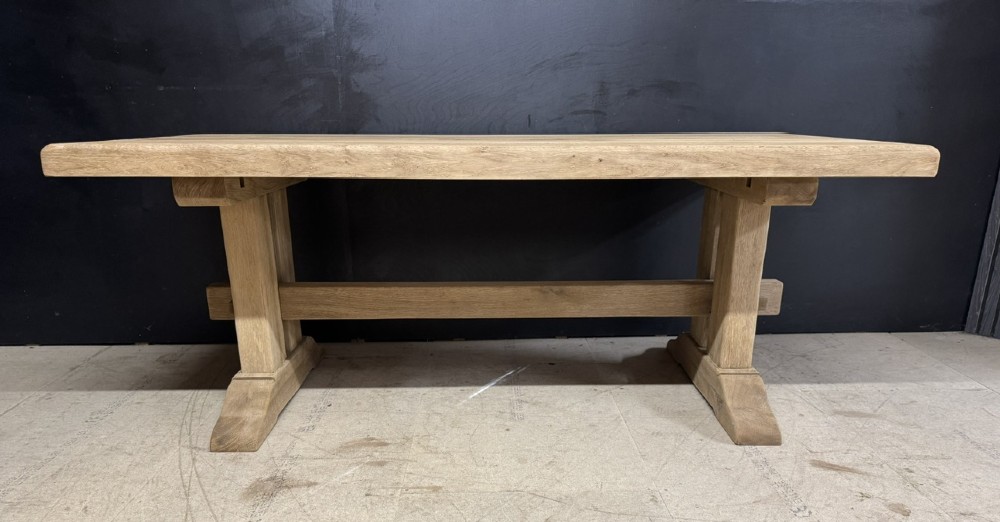 A solid bleached oak dining table featuring a thick rectangular top supported by a sturdy trestle base and central stretcher rail. View VII