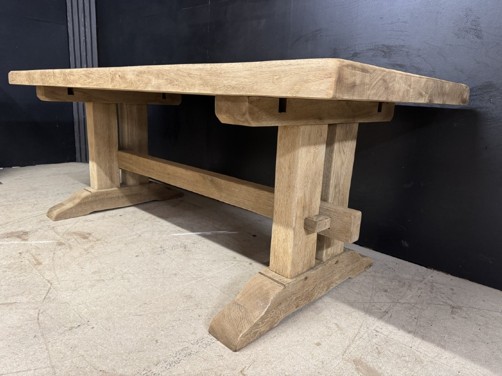 A solid bleached oak dining table featuring a thick rectangular top supported by a sturdy trestle base and central stretcher rail. View IX