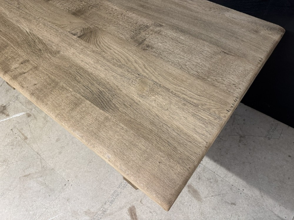 A solid bleached oak dining table featuring a thick rectangular top supported by a sturdy trestle base and central stretcher rail. View XII