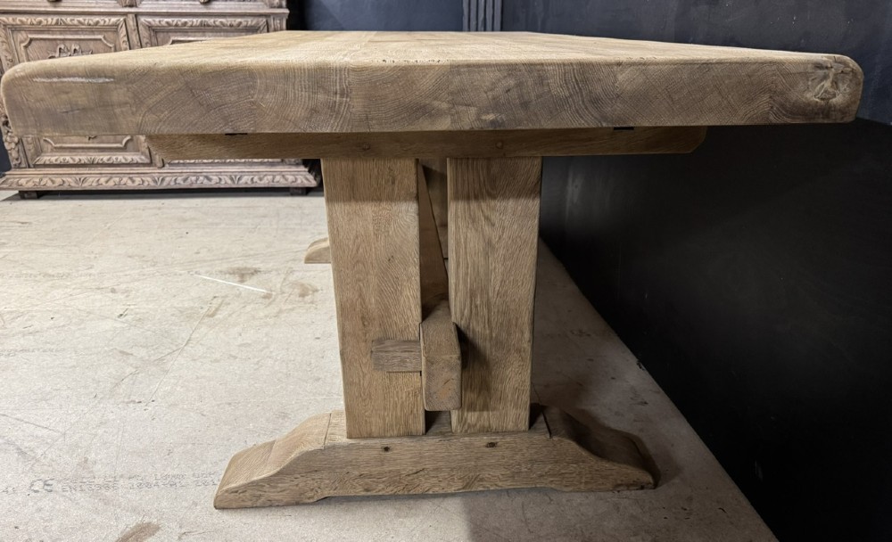 A solid bleached oak dining table featuring a thick rectangular top supported by a sturdy trestle base and central stretcher rail. View XIV