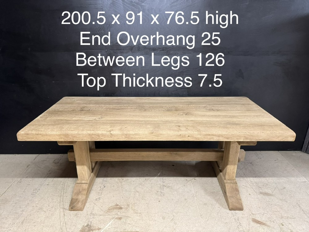 A solid bleached oak dining table featuring a thick rectangular top supported by a sturdy trestle base and central stretcher rail. View XV