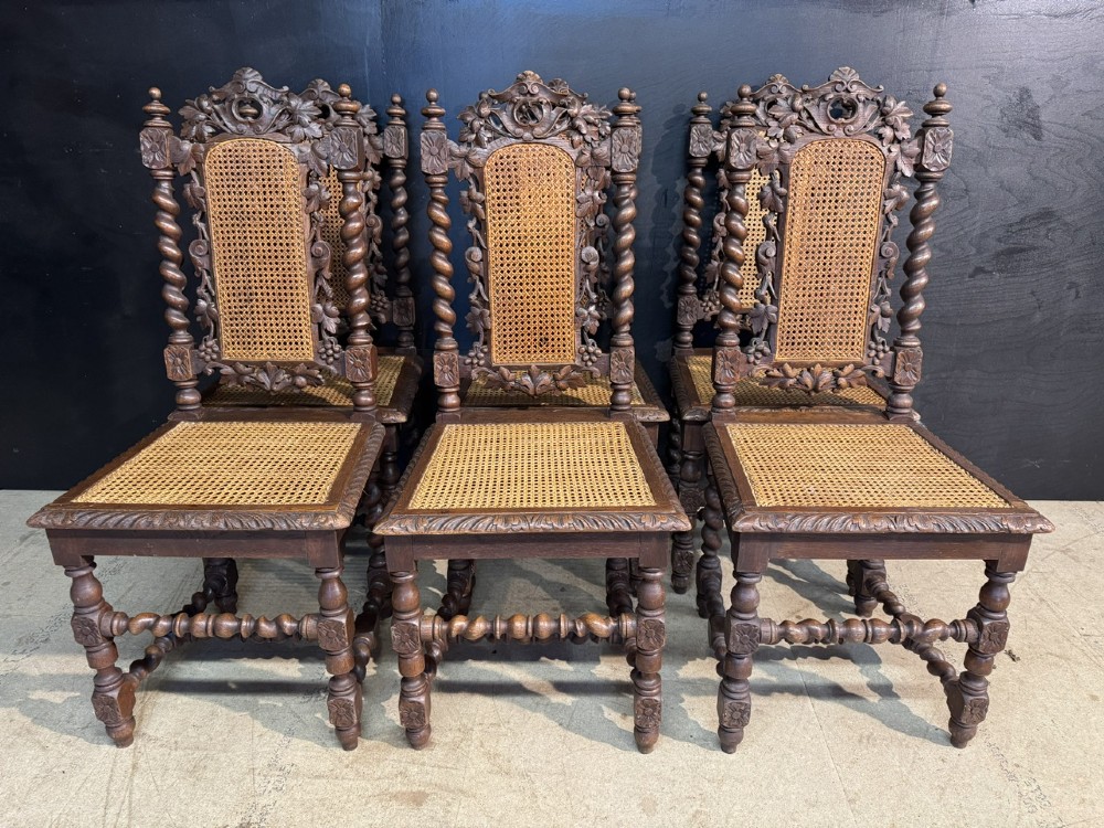 A set of six dark oak dining chairs with carved crestings, barley twist supports, and woven cane panels. View V