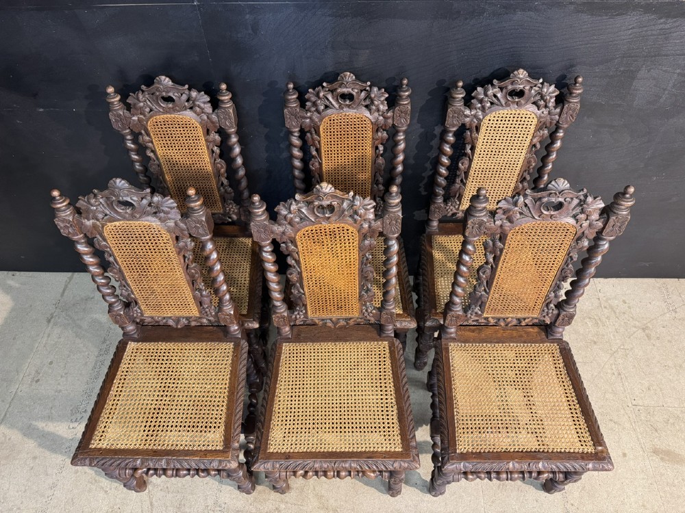 A set of six dark oak dining chairs with carved crestings, barley twist supports, and woven cane panels. View VI