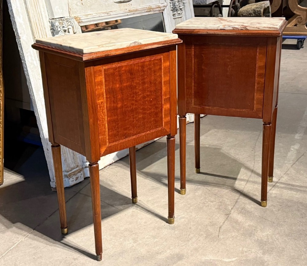 A pair of French Louis XVI style wooden bedside cabinets featuring marble tops, single drawers, inlaid cupboard doors, and gilt brass mounts on slender tapered legs. View IV