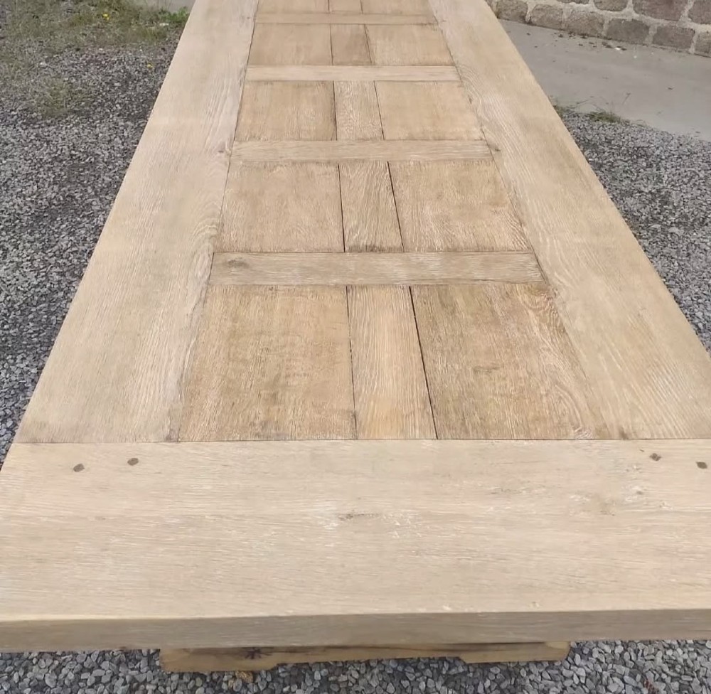 A three-metre long light oak farmhouse refectory table featuring a panelled top and a heavy trestle base. View III