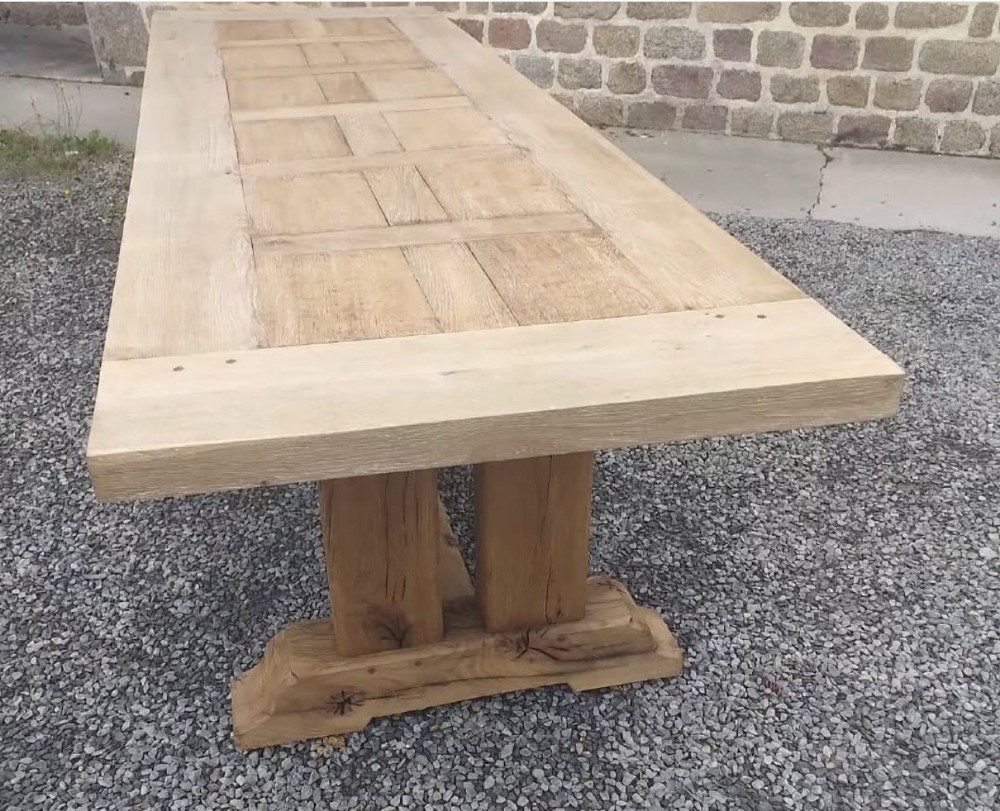 A three-metre long light oak farmhouse refectory table featuring a panelled top and a heavy trestle base. View IV
