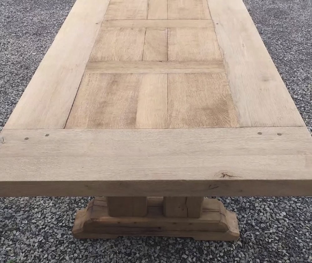 A three-metre long light oak farmhouse refectory table featuring a panelled top and a heavy trestle base. View V