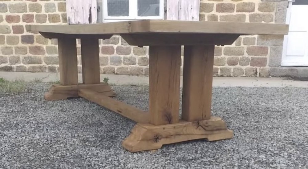 A three-metre long light oak farmhouse refectory table featuring a panelled top and a heavy trestle base. View VI