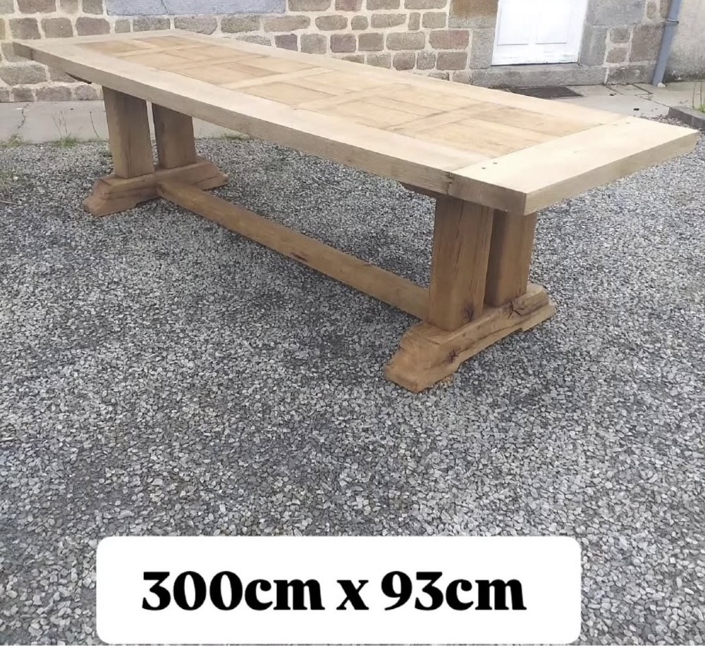 A three-metre long light oak farmhouse refectory table featuring a panelled top and a heavy trestle base. View VII