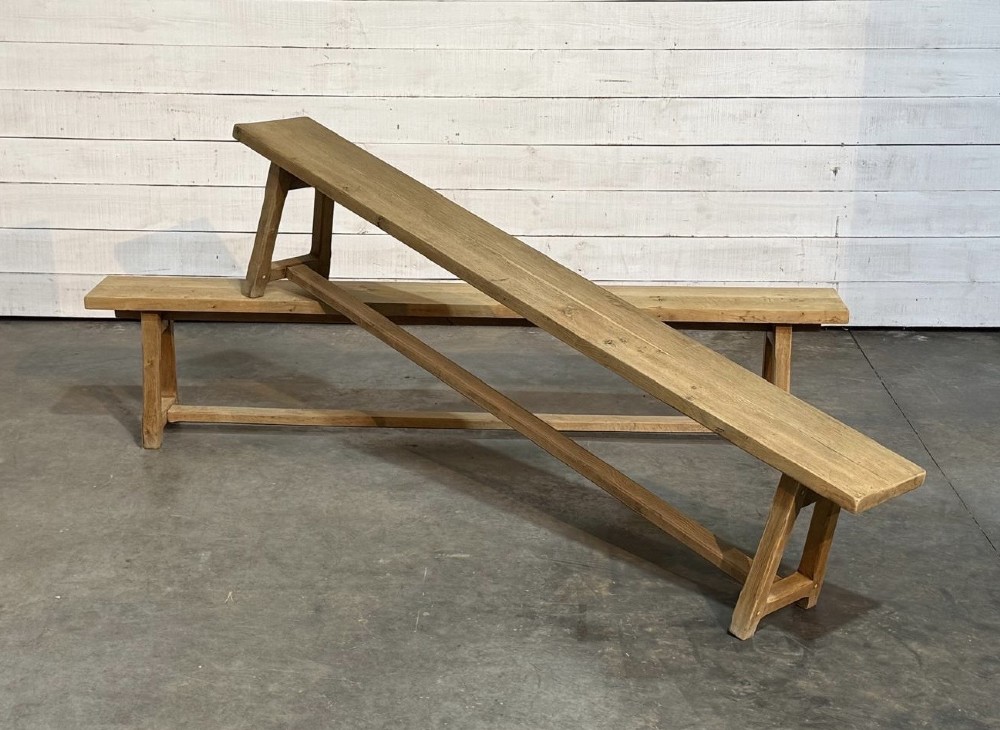 A pair of long rustic light oak dining benches with A-frame legs and cross-stretchers.