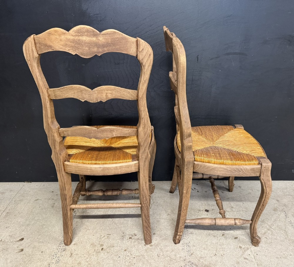 A set of eight French farmhouse dining chairs featuring carved wooden ladderback frames, woven rush seats, and cabriole front legs. View V