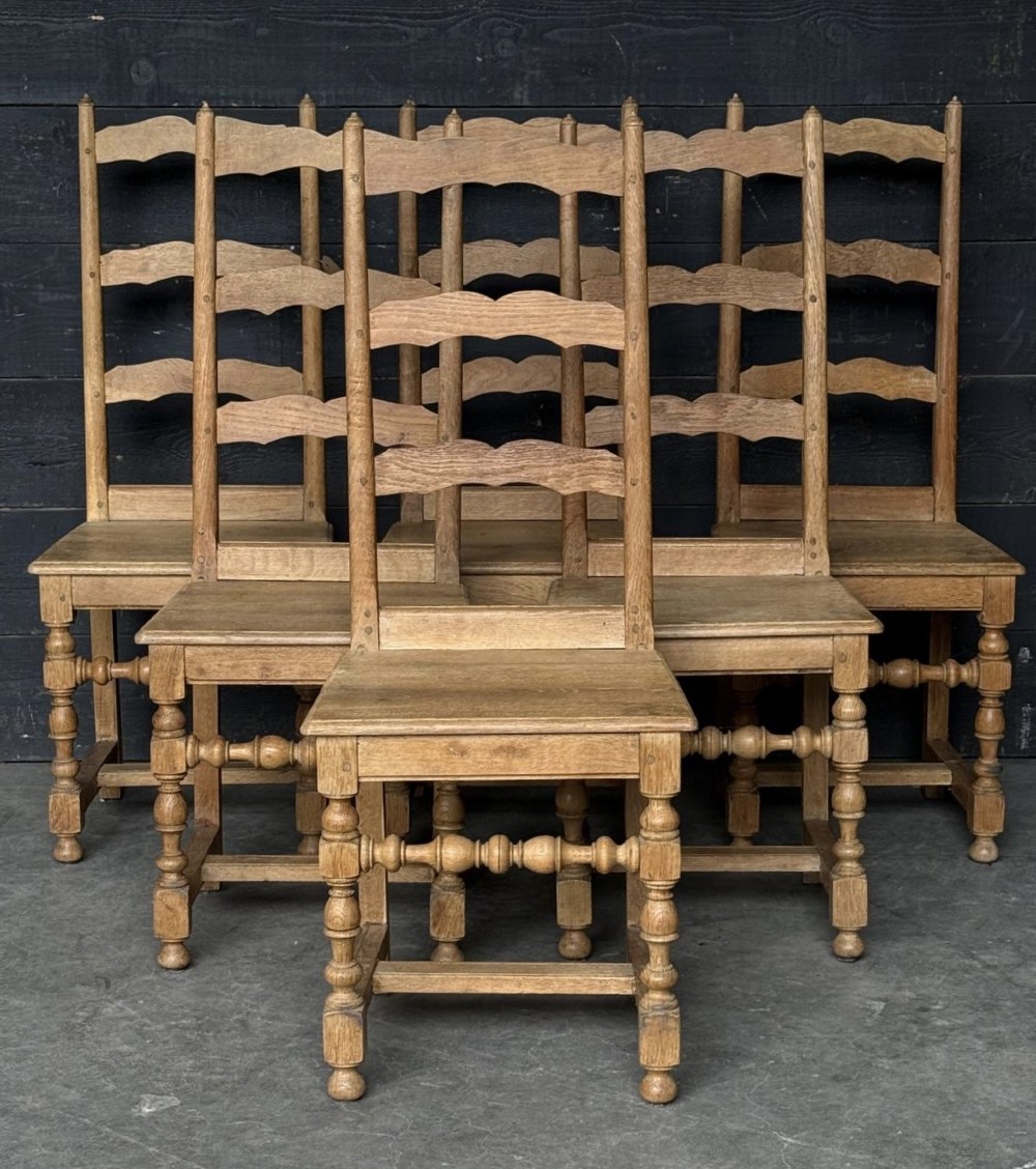 A set of six light oak ladderback dining chairs featuring wavy back slats, turned legs, and solid wooden seats.