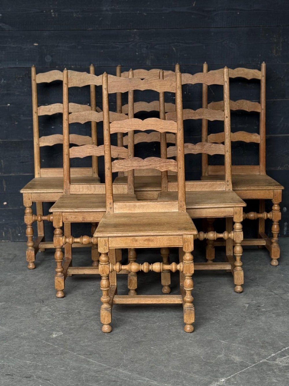 A set of six light oak ladderback dining chairs featuring wavy back slats, turned legs, and solid wooden seats. View III