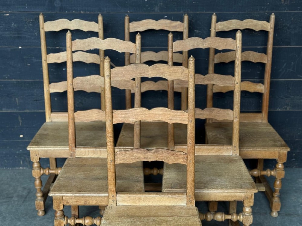 A set of six light oak ladderback dining chairs featuring wavy back slats, turned legs, and solid wooden seats. View V