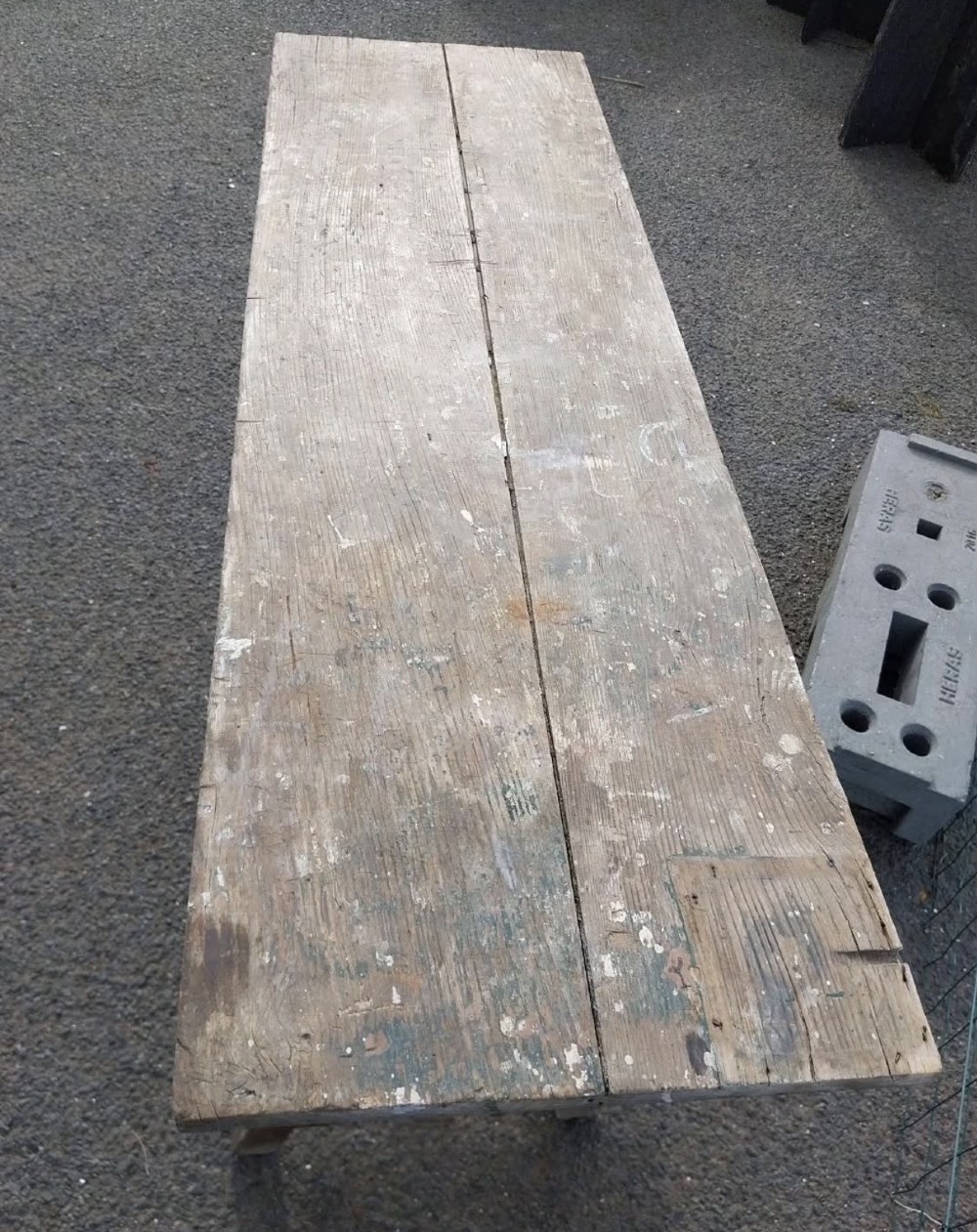 A rustic weathered wooden French laundry table featuring a plank top supported by angled A-frame trestle legs and a central stretcher. View VI