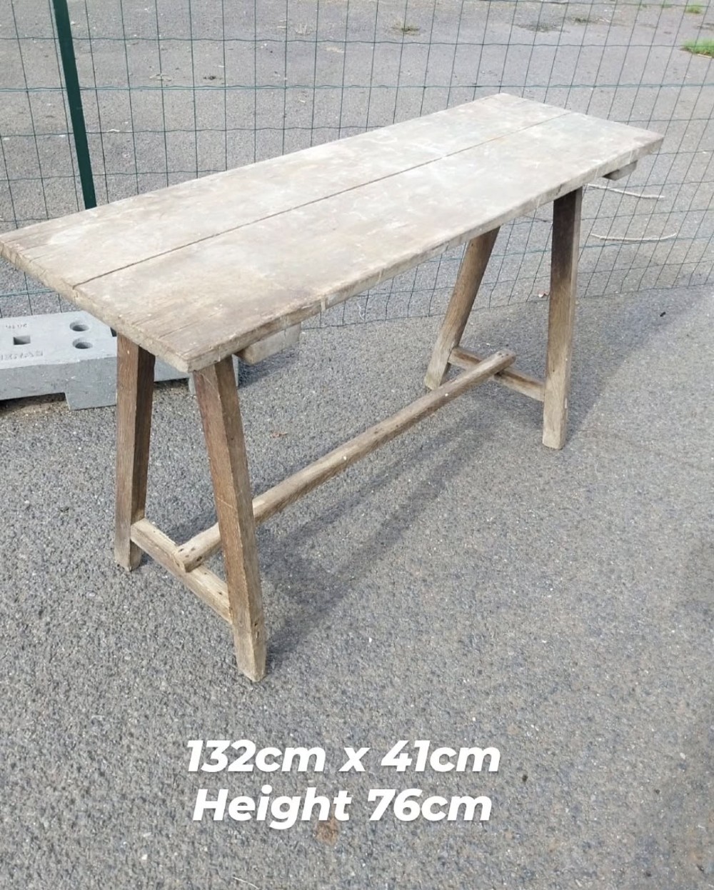 A rustic weathered wooden French laundry table featuring a plank top supported by angled A-frame trestle legs and a central stretcher. View VIII